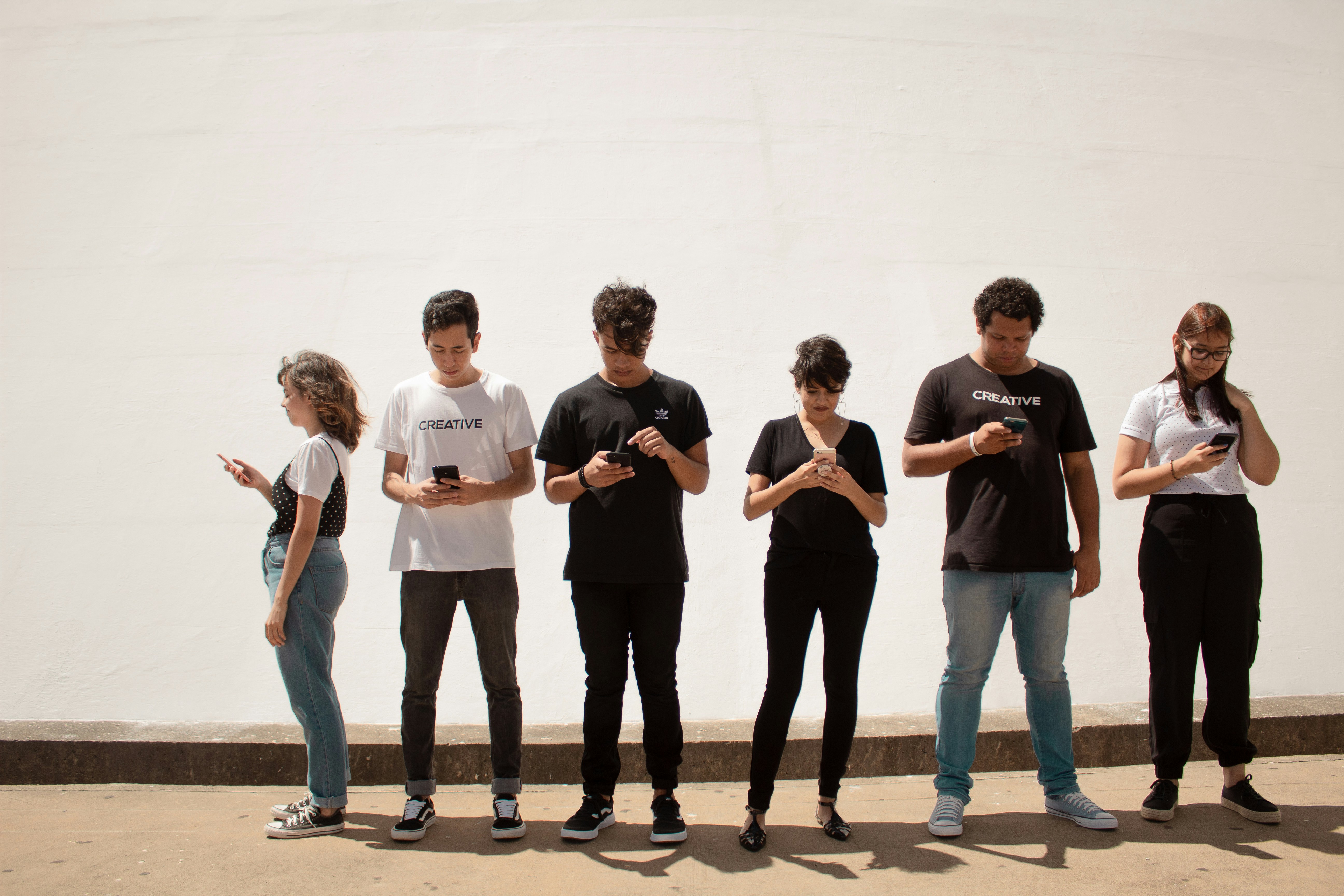 Young people absorbed in their phones, illustrating the impact of social media on attention and critical thinking
